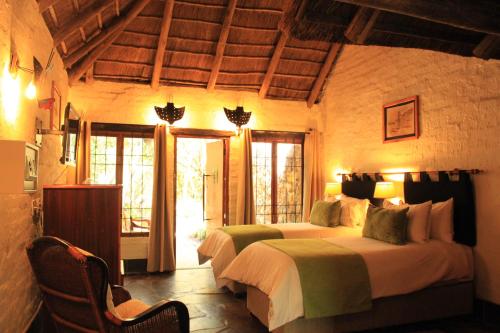 a bedroom with two beds in a room with windows at Misty Hills Country Hotel, Conference Centre & Spa in Muldersdrift