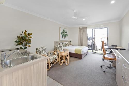 a hotel room with a bed and a kitchen with a sink at Beachside Boutique Motel Mackay in Mackay