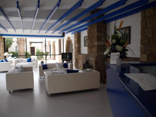 a living room with white couches and blue ceilings at Hilltop Gardens Hotel Apartments in Paphos