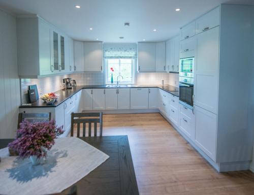 a large kitchen with white cabinets and a table at Viken Holiday Home in Viksdalen