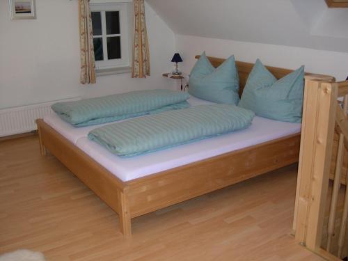 ein Holzbett mit blauen Kissen darüber in der Unterkunft Ferienhaus Ehrenreith in Göstling an der Ybbs