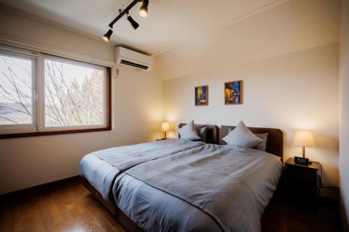 a bedroom with a large bed and a window at Villa Qualite ヴィラカリテ in Zao