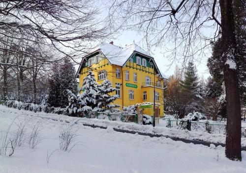 a large yellow house with snow on the ground at Pensjonat Eldorado in Świeradów-Zdrój