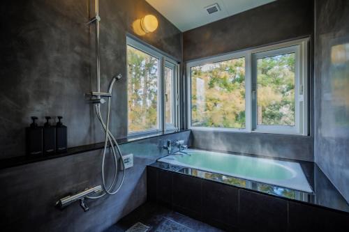 a bathroom with a bath tub and a window at Villa Qualite ヴィラカリテ in Zao