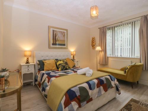 a bedroom with a bed and a chair and a window at Gwylan Uchaf in Y Felinheli