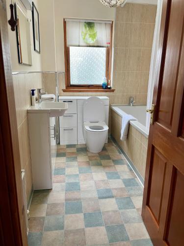 a bathroom with a toilet and a sink and a tub at Brackenbrae Holiday Cottage in Acharacle