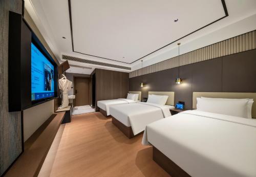 a hotel room with four beds and a flat screen tv at Tuke Light Hotel Jiuzhaigou 途客轻居酒店九寨沟店 in Jiuzhaigou