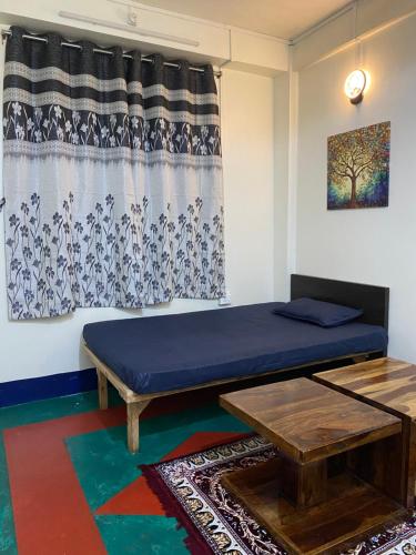 a room with a bed and a table and a curtain at Pine Forest Home stay with City View in Shillong