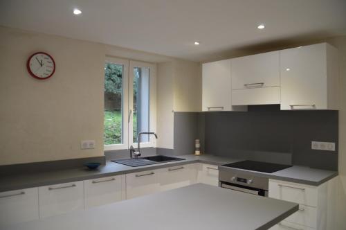 une cuisine avec des placards blancs et une horloge murale dans l'établissement maison corse en balagne, à Cateri