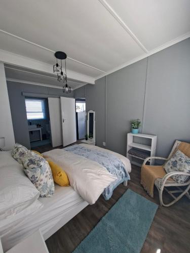 a bedroom with a large bed and a chair at 7onthebeach unit 3 in Jeffreys Bay