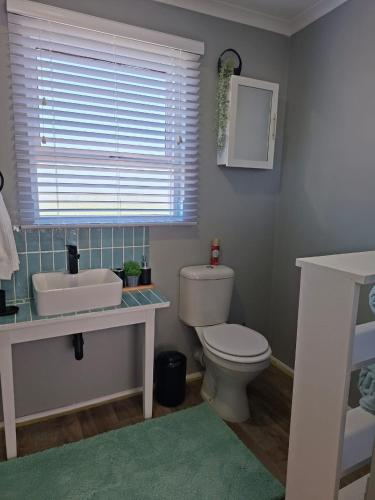 a bathroom with a toilet and a sink and a window at 7onthebeach unit 3 in Jeffreys Bay