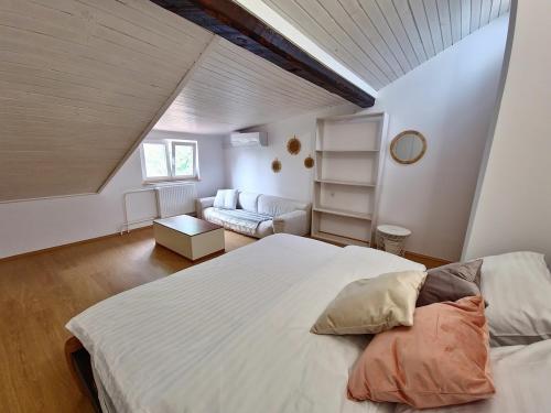 a bedroom with a large white bed and a couch at Apartment Učka Home in Tuliševica