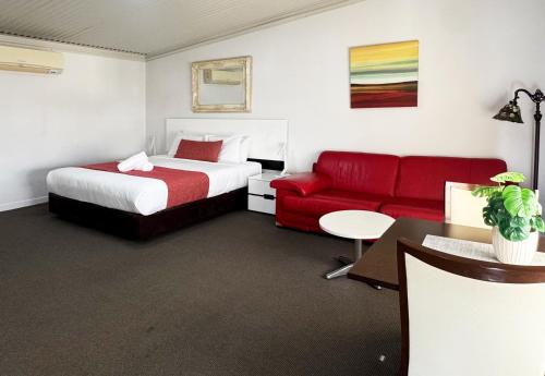 a hotel room with a bed and a red couch at Gunnedah Lodge Motel in Gunnedah