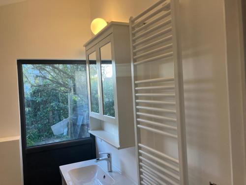 a bathroom with a sink and a mirror and a window at The Tiny House in Nieuwpoort
