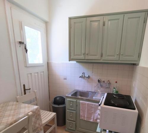 a kitchen with white cabinets and a sink and a window at Klimatsias Beach Apartment in Pesádha