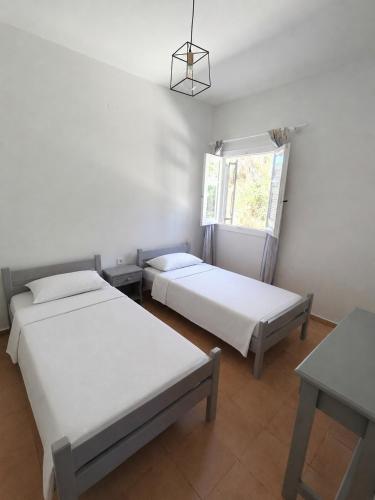 a room with two beds and a window at Klimatsias Beach Apartment in Pesádha