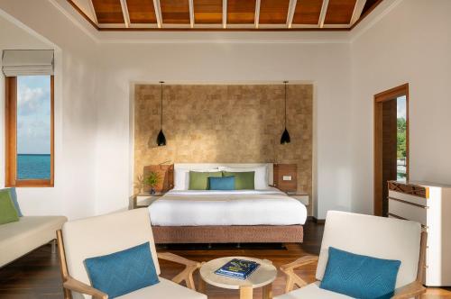 a bedroom with a bed and two chairs at Kandolhu Maldives in Mushimasgali
