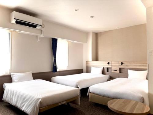a hotel room with two beds and a table at Smile Hotel Kitaasaka in Asaka