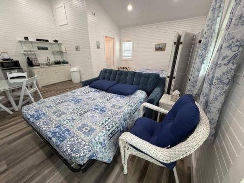 a bedroom with a bed and chairs and a kitchen at Romantic Tea Cottage with Deck and Nature in Cape Girardeau