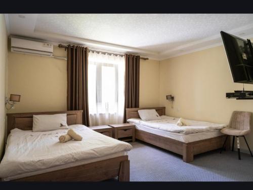 a room with two beds and a tv on the wall at Tem Hotel in Khorog