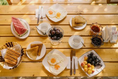 a wooden table topped with plates of breakfast foods at Tem Hotel in Khorog