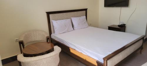 a bedroom with a bed with a table and a chair at Bam Asia Five Star Hotel in Bāmīān