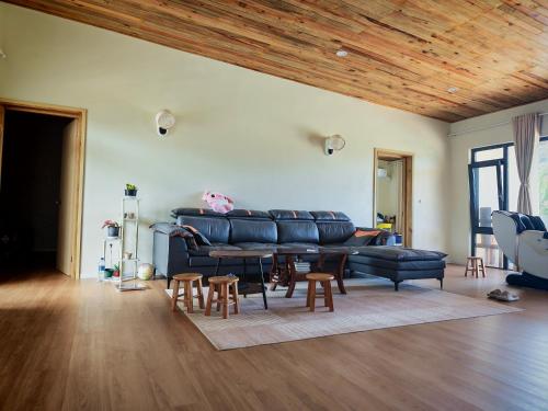 a living room with a black leather couch and wooden ceilings at villa 911 in Pacific Harbour