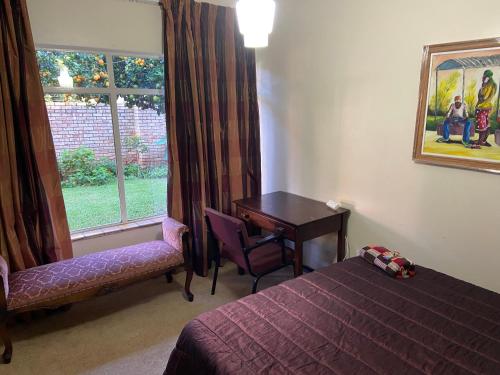 a bedroom with a bed and a desk and a window at Highway Haven in Stilfontein
