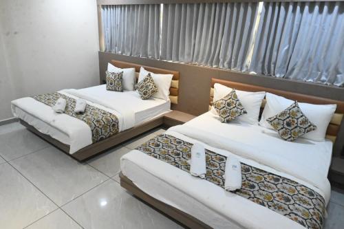 two beds in a hotel room with white sheets at Hotel Crystal in Ahmedabad