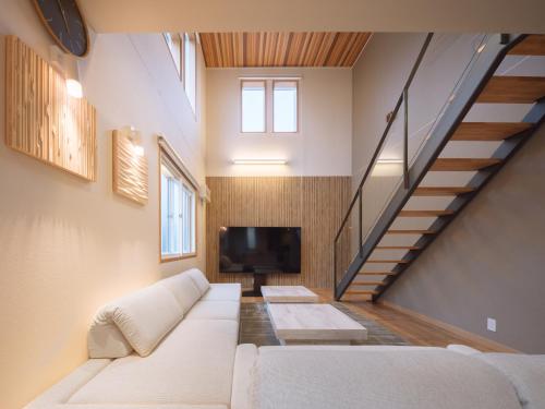 a living room with a white couch and a tv at マークヴィラ松本 in Matsumoto