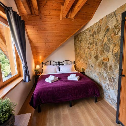 a bedroom with a bed with a stone wall at Panorama Lodge in Pec pod Sněžkou