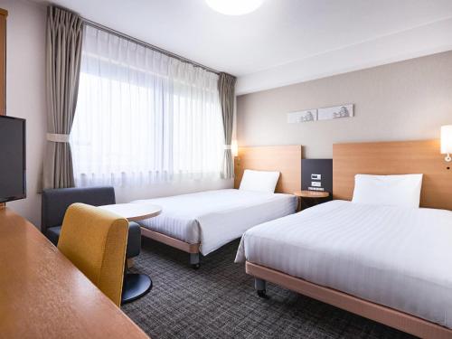 a hotel room with two beds and a tv at Comfort Hotel Himeji in Himeji