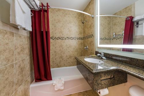 a bathroom with a sink and a red shower curtain at Rodeway Inn South San Francisco Airport in South San Francisco