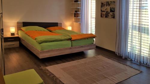 a bedroom with a bed with green sheets and orange pillows at Ferienwohnung Dolomitenpanorama in Oberlienz