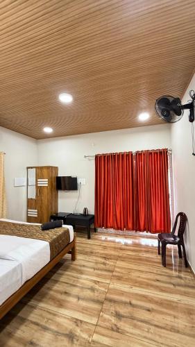 a bedroom with two beds and a red curtain at The Royal Pool Resort-Swimming Pool Resort, Varkala in Varkala