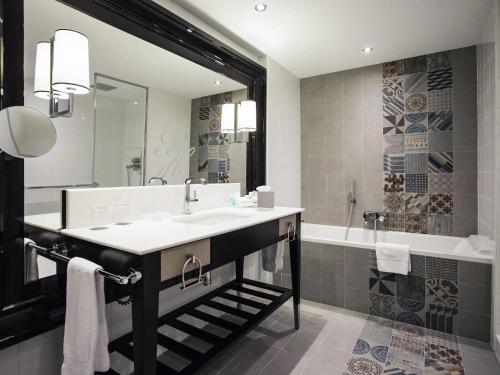 a bathroom with a sink and a tub and a mirror at Park Hotel Grenoble - Handwritten Collection in Grenoble