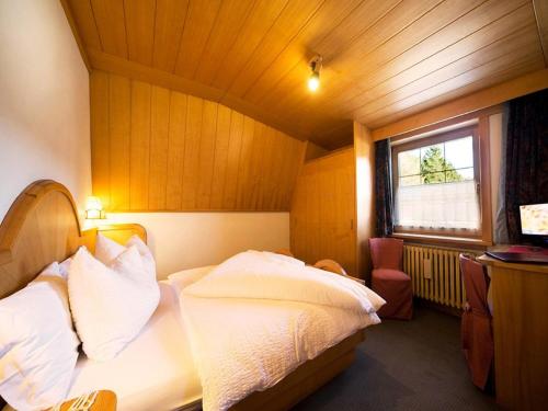 1 dormitorio con 1 cama con sábanas blancas y ventana en Hotel Villa Wilma, en Folgaria