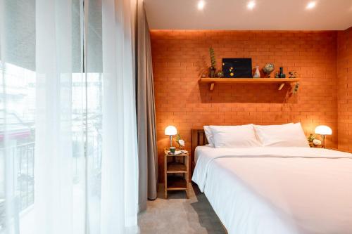 a bedroom with a white bed and a brick wall at Easterly Room 01 in Chanthaburi
