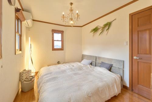 a bedroom with a bed and a chandelier at Villa上条 名古屋から30分本格ガスグリルでBBQができる宿 in Kasugai
