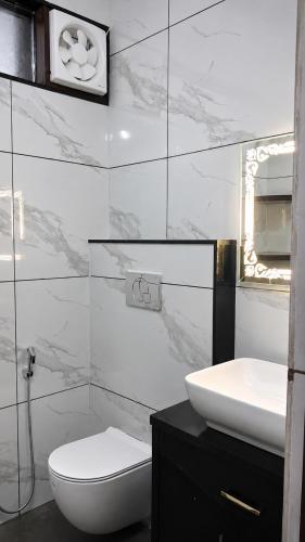 a white bathroom with a toilet and a sink at Moti Manas Mansion - A Homestay in Gwalior in Gwalior