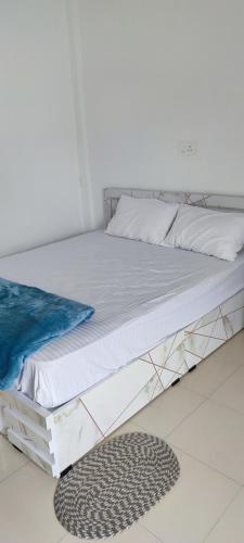 a bed with white sheets and a rug on the floor at Kanchan Grace in Vaduvanchal