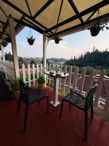a table and chairs on a porch with a view at Rosewood Camellia - Near Ooty Town in Ooty