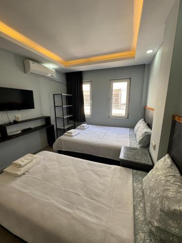 a bedroom with two beds and a flat screen tv at Kışla Pansiyon in Antalya