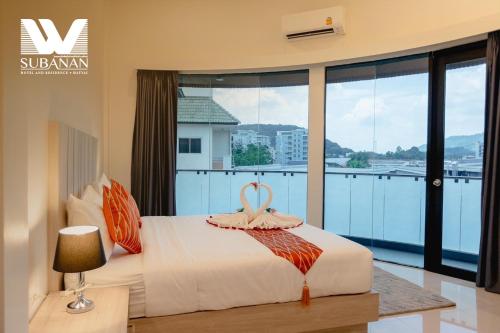 a bedroom with a bed and a large window at SUBANAN Hotel and Residence, Hatyai - โรงแรมทรัพย์อนันต์ เรสซิเด้นซ์ หาดใหญ่ in Hat Yai