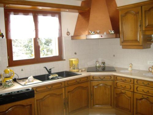 una cocina con armarios de madera y fregadero en appartement vue sur la montagne, en Soultzeren