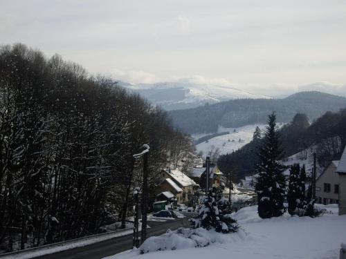 una ciudad cubierta de nieve con una pista de esquí a lo lejos en appartement vue sur la montagne en Soultzeren