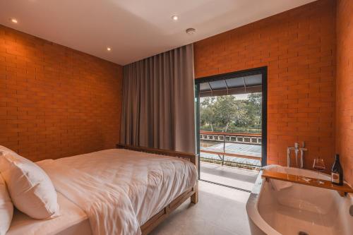 ein Schlafzimmer mit Bett, Fenster und Badewanne in der Unterkunft Easterly Room 02 in Chanthaburi