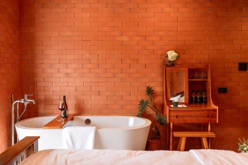 ein Badezimmer mit einer weißen Badewanne und einer roten Backsteinwand in der Unterkunft Easterly Room 02 in Chanthaburi