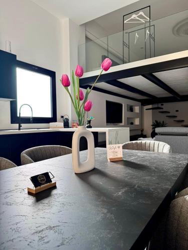 ein Tisch mit einer Vase mit rosa Blumen darauf in der Unterkunft The loft 87 in San Giovanni in Fiore