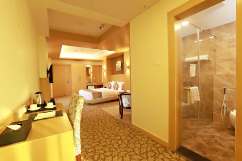 a hotel room with a bathroom with a bed and a shower at Hotel Patliputra Continental in Patna